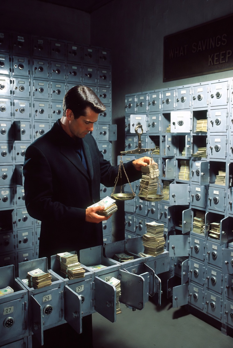 An archive of lockboxes holding stacks of banknotes beside a balance scale